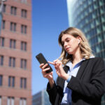 Persoană tânără lucrând de pe telefon într-un mediu modern